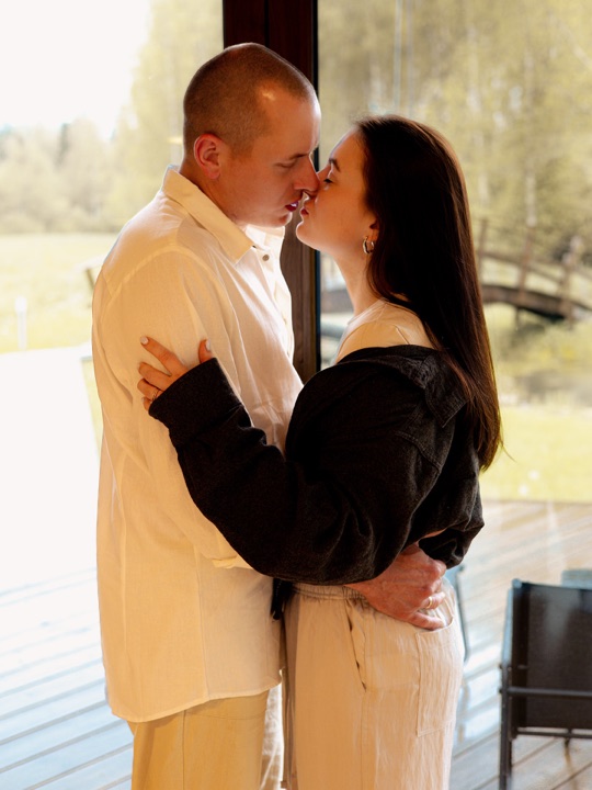 A couple together beside a large window