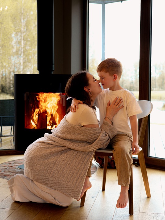 A mother embracing her son beside a fireplace
