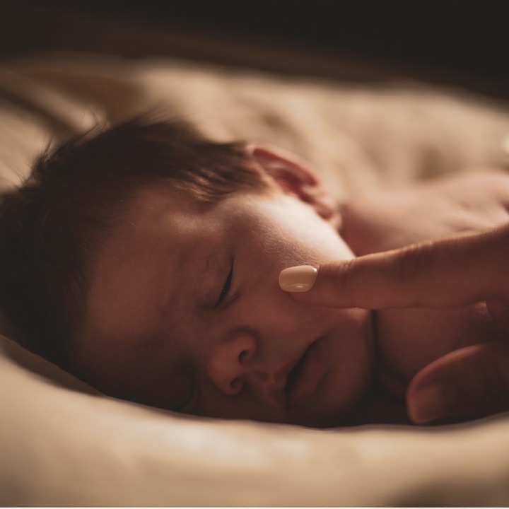 A sleeping baby with a gentle touch on the cheek