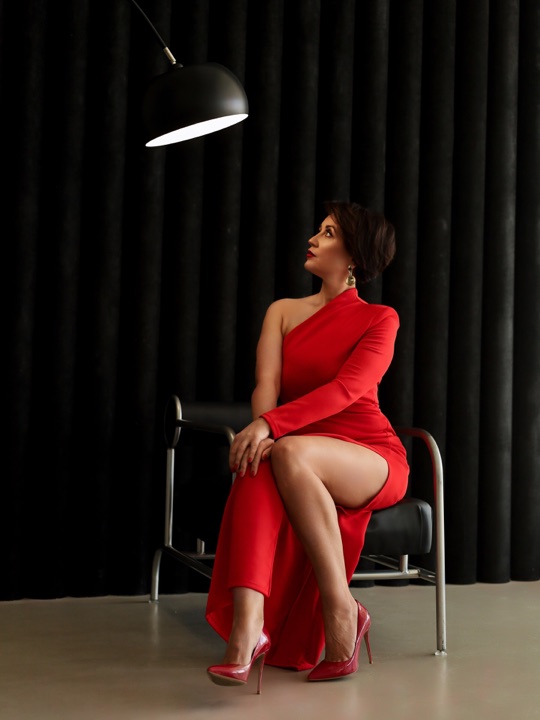 Portrait in a red dress seated beneath a lamp