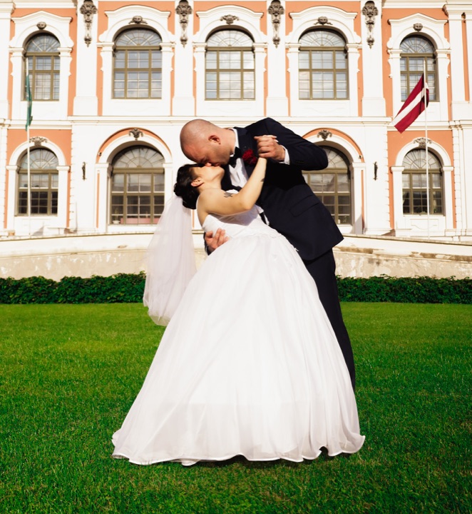 A wedding couple embracing outside a light-coloured building