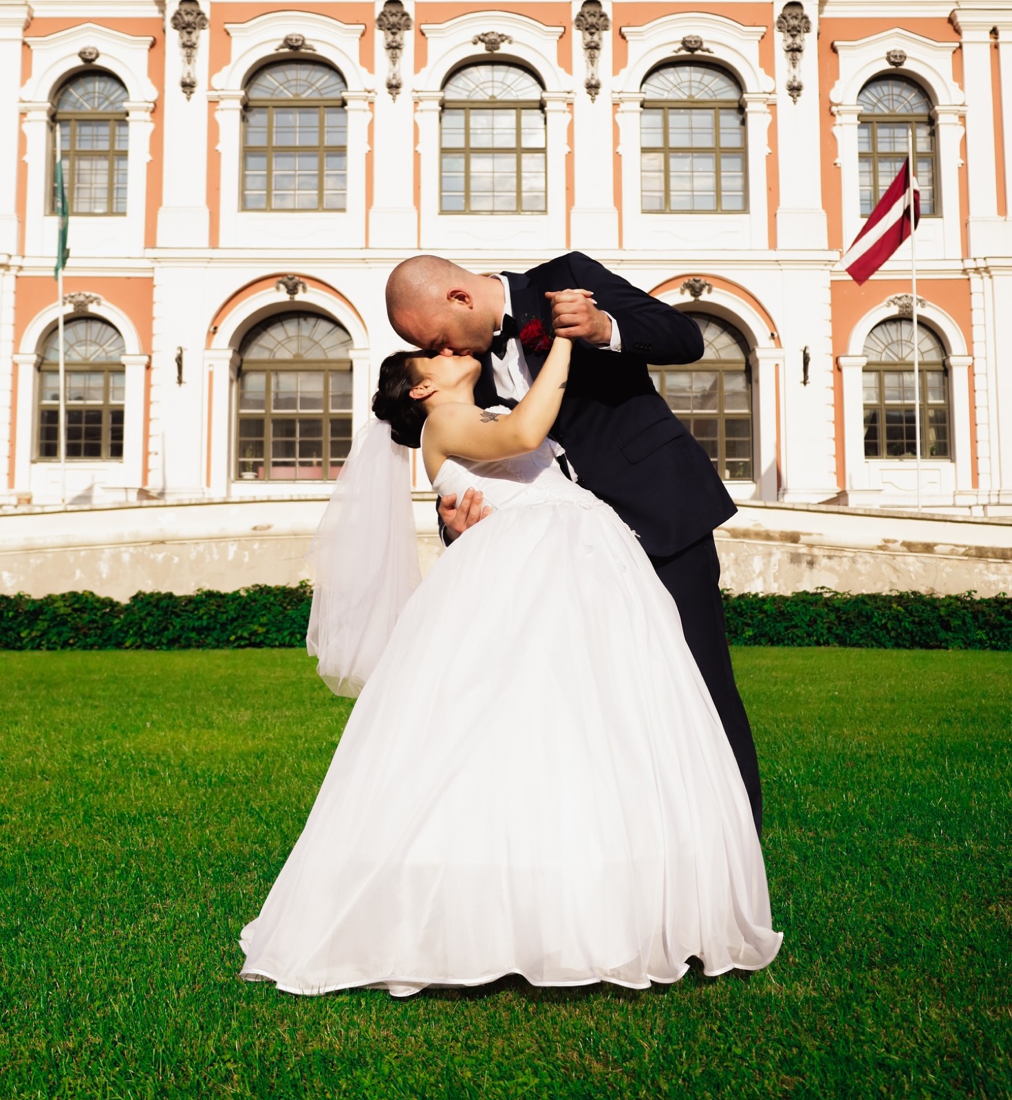 A wedding couple embracing outside a light-coloured building
